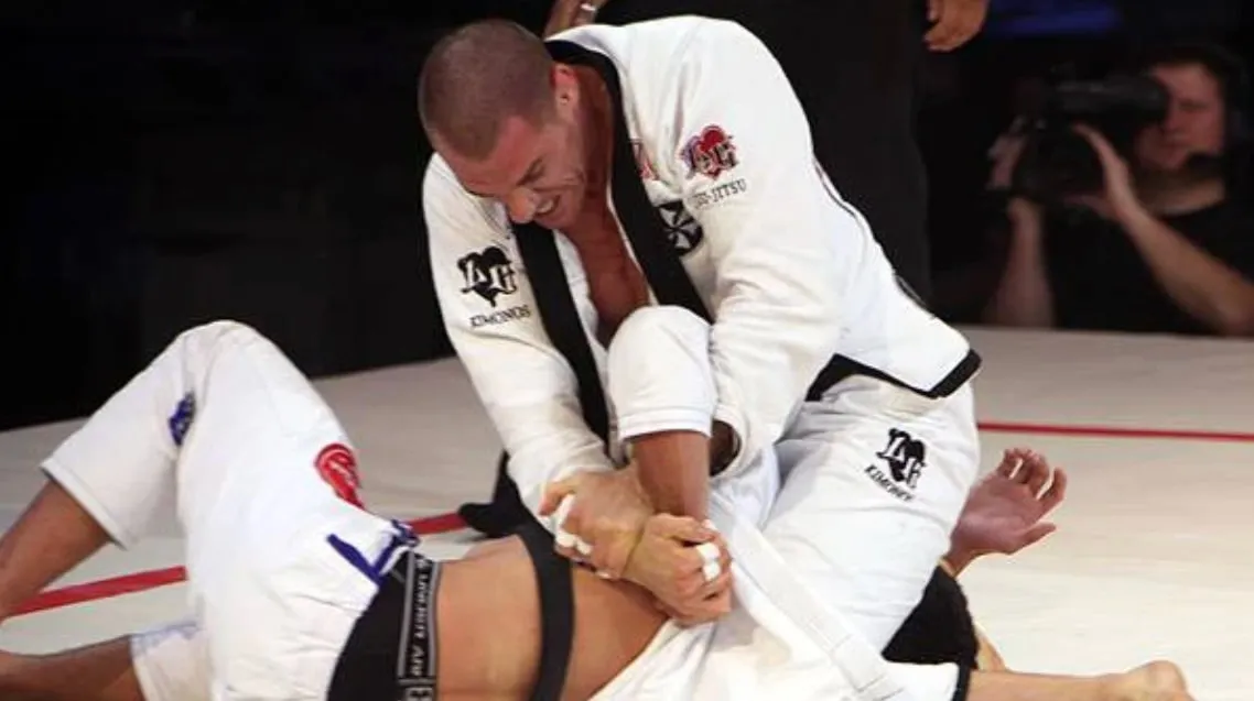 A competitor securing a figure-four Kimura grip on his opponent's trapped arm during a black belt match